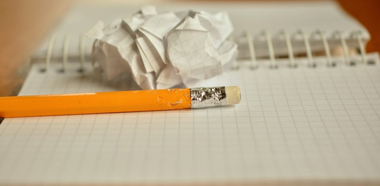 Un crayon et d'une feuille roulée en boule posés sur un cahier à spirales